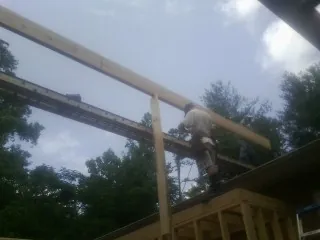 Carpenter setting a ridge beam over a new addition frame — Ice Dam Removal by Roofing Brothers in Erskine
