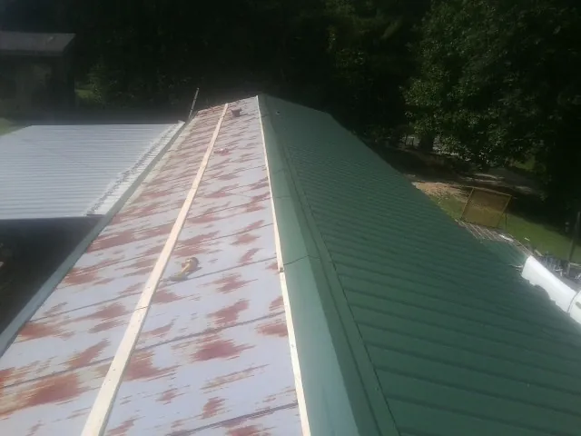 Old rusted panels beside newly installed green metal roofing — Wind Damage Roof Repair by Roofing Brothers in Erskine