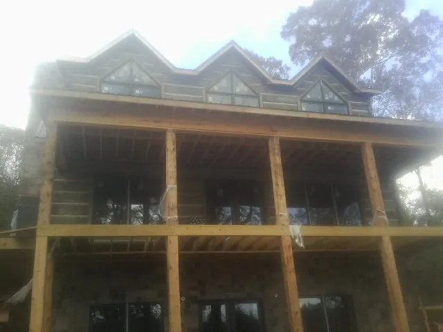 Dormers and porch framing on a large log home under construction — Roof Coating work by our crew in Erskine