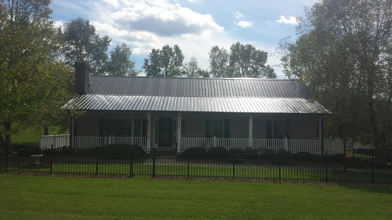 Gray metal roof on a brick ranch with a full width front porch — Gutter Guard Installation work by our crew in Erskine