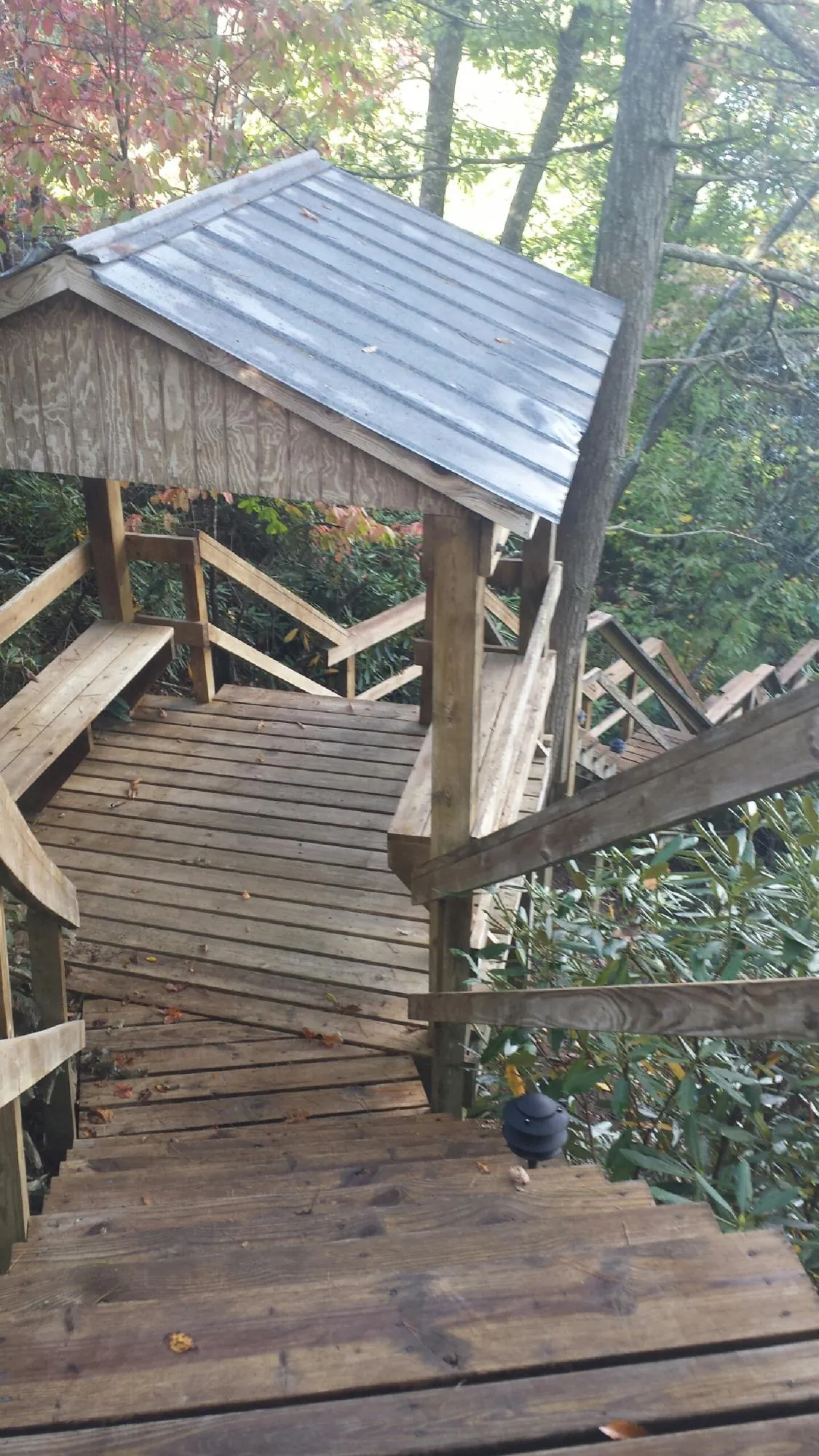 Metal roofed shelter over wooden steps on a wooded walkway — Skylight Repair & Installation work by our crew in Erskine