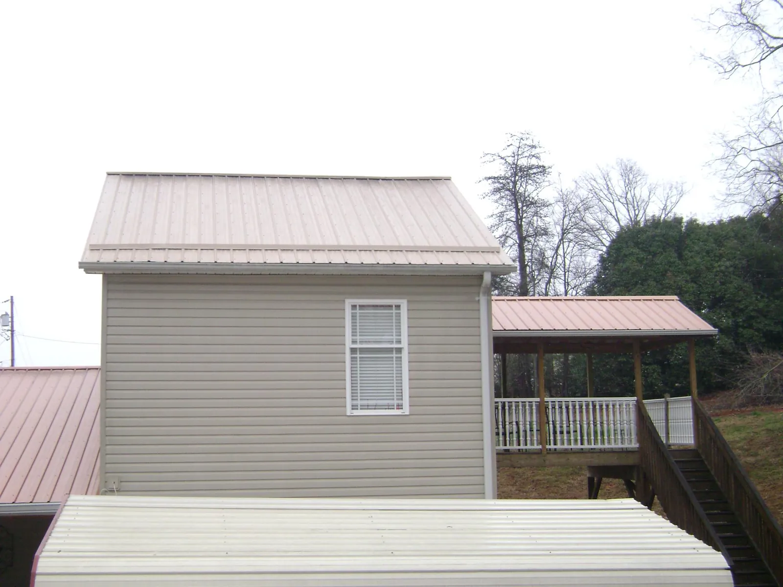 Tan metal roofs on a two story addition and attached porch, from a Roof Replacement job in Erskine