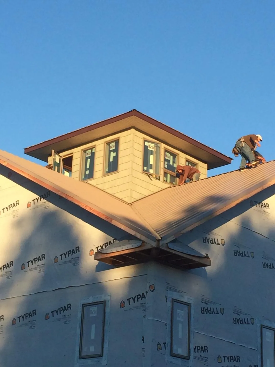 Roofers working around a rooftop cupola on a new metal roof at sunset — Roof Waterproofing in Erskine by Roofing Brothers